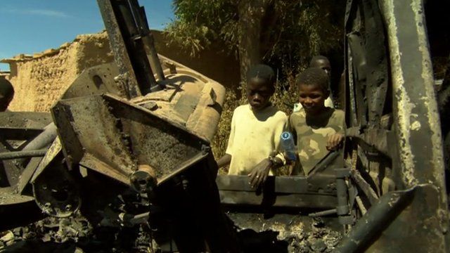 Children rest on charred vehicle