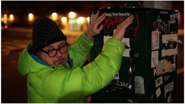 A man affixes a protest sticker to a utilities box
