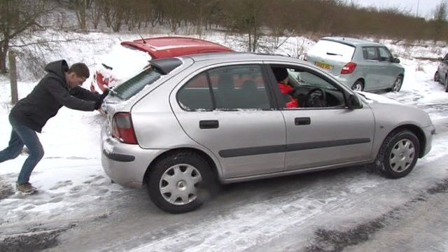 Man pushing car on snowy road