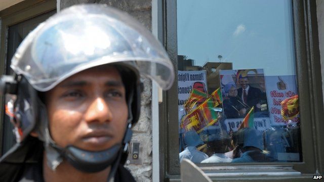 Pro-government activists are reflected in the glass of the US embassy during a protest in Colombo