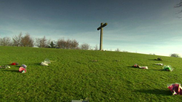A cross surrounded by with scattered flowers