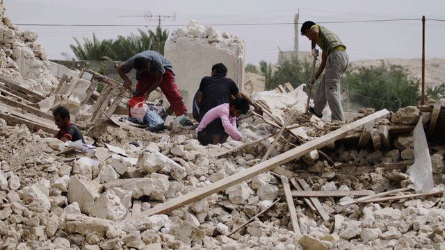 Iranians collect their belongings from the rubble of a destroyed house