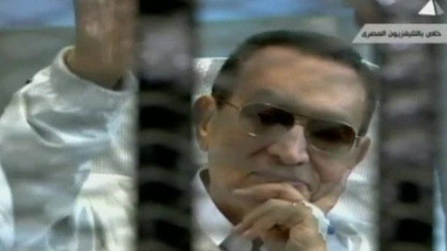 Hosni Mubarak in court, smiling and waving
