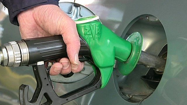 A hand holding a petrol pump to fill up a car