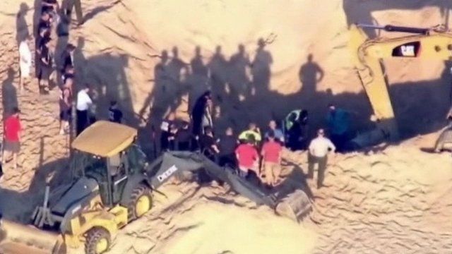 Rescuers and diggers at sand dune