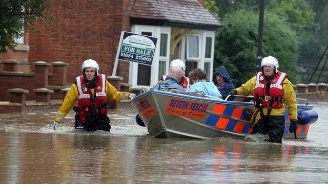 A fire rescue boat takes people from their home after heavy flooding