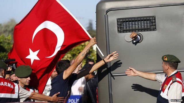 Protesters run after a prison van as an unidentified defendant sticks his fist out outside the courthouse in Silivri