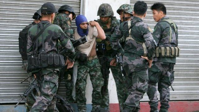Combat police forces check on their comrade (centre) who was hit by sniper fire in downtown Zamboanga in the Philippines on 9 September 2013