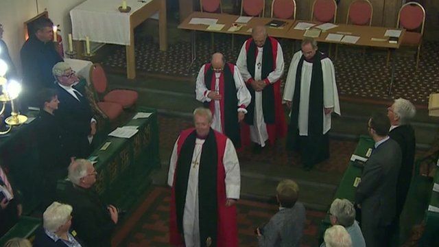Four male bishops inside a Church.