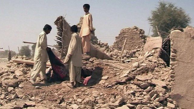 People standing near damaged buildings