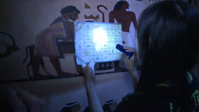 Woman with torch reading hieroglyphics