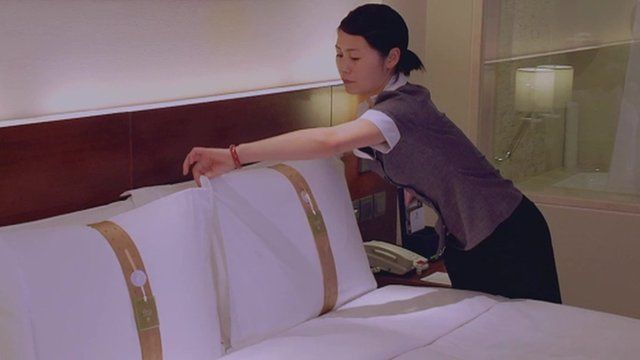 Hotel worker turning down bed