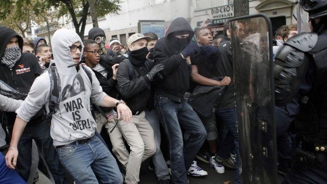 Highschool students face riot police officers as they demonstrate against the police expulsions of immigrant families, including some of their classmates
