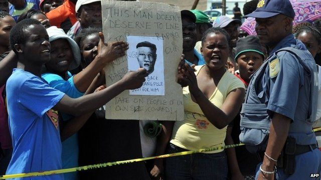 A police officer by protesters demonstrating in Diepsloot, north of Johannesburg, over the rape and murder of two toddlers - Friday 18 October 2013