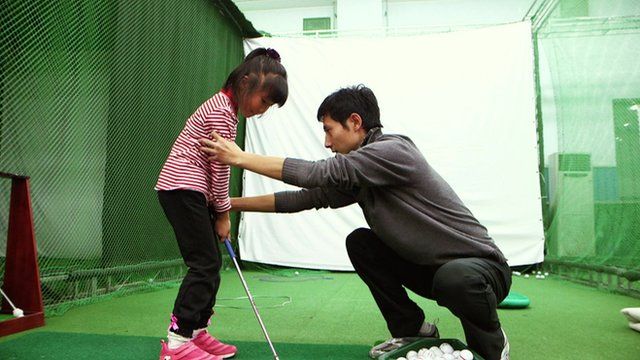 A coach adjusts a child's stance