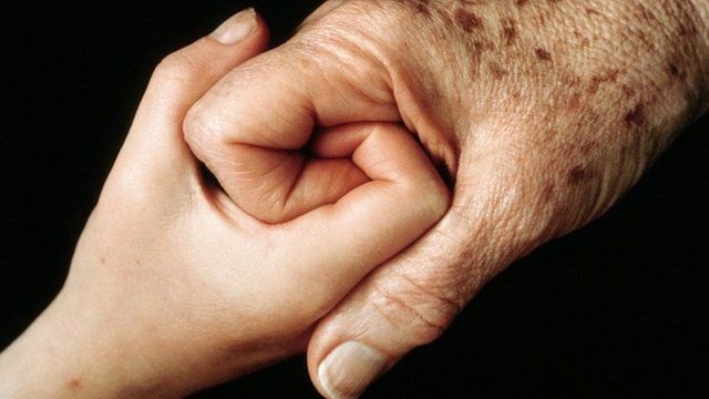 younger and older person holding hands