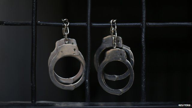 Handcuffs hang from prison bars