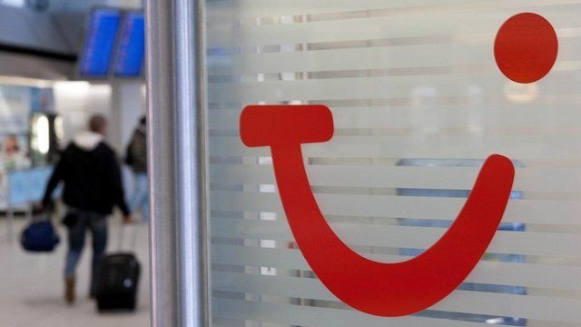Man walking past Tui logo at airport