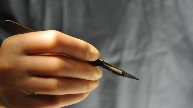 A hand holding a scapel