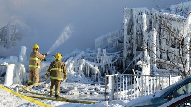 Canadian fire-fighters douse the burnt remains of a retirement home in L'Isle-Verte