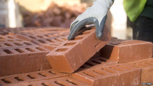 Person picking up a brick