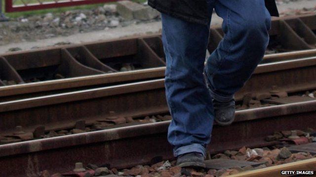 An immigrant crosses railway tracks in Calais, France