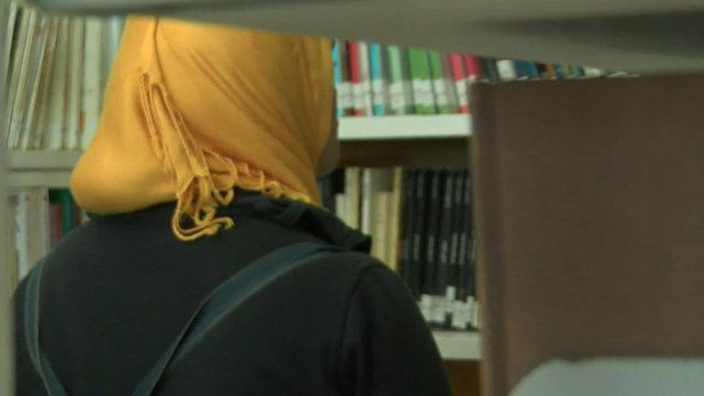 A woman in a headscarf looks at books