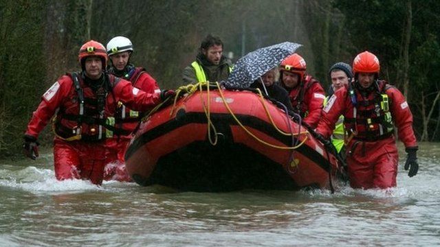 Firefighters rescue a woman from her house in Wraysbury, Berkshire