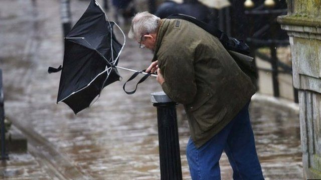 A man struggles to control his umbrella in Windsor, Berkshire