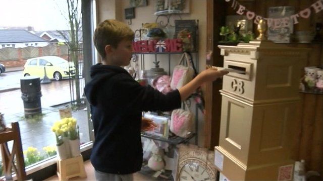 Boy posting letter into gold postbox