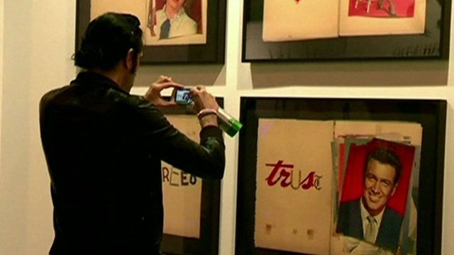 A young man takes a photograph of an artwork at the fair