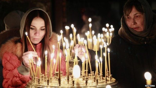 People light candles during a religious service at a church in Kiev