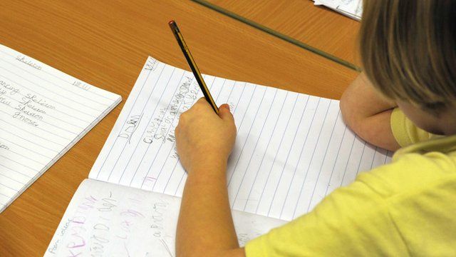 Left-handed child writes in a book