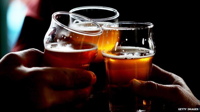 Three men clink their pint glasses