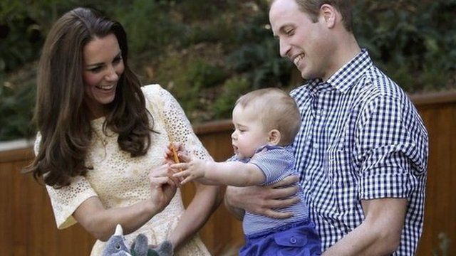 Britain's Catherine, Duchess of Cambridge, gives her son George a commemorative card as he is held by his father Prince William