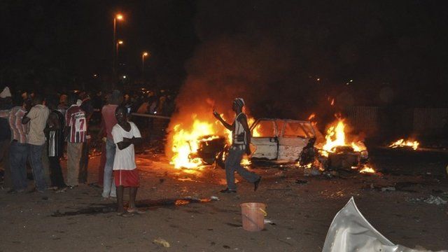 People gather at the site of a car bomb explosion in Abuja, Nigeria