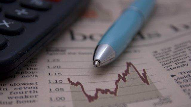 Calculator and pen on top of a financial newspaper