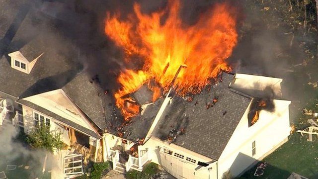 In this frame grab from television helicopter video, a home bursts into flames in Brentwood, N.H