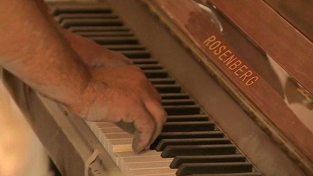 Man plays dusty piano inside Homs