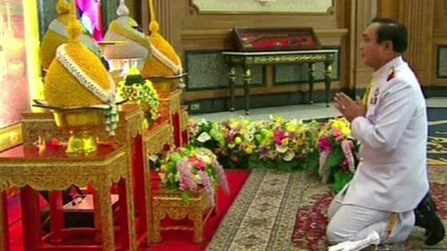 General Prayut Chan-O-Cha paying respects in front of a portrait of Thai King Bhumibol Adulyadej