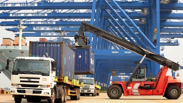 Shipping containers being loaded onto trucks from a cargo ship at Tianjin port, China