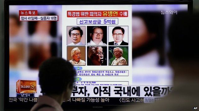 A woman watches a TV news programme showing the reward poster of Yoo Byung-eun