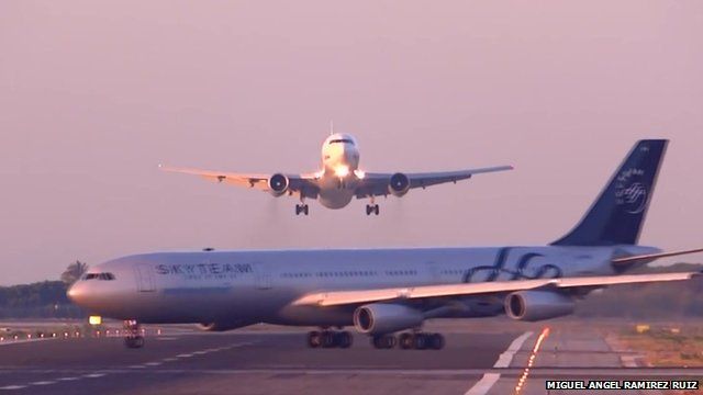 An Airbus 340 is shown crossing the runway at El Prat Airport as a flight from Moscow is coming in to land