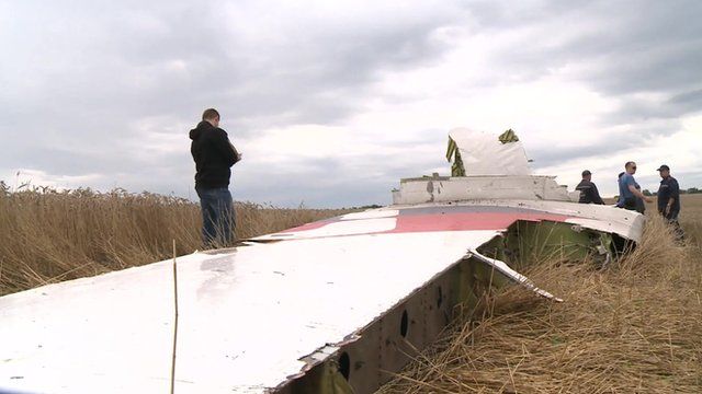 Men stand around a plane wing