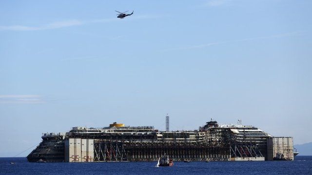 A military helicopter flies over the cruise liner Costa Concordia during refloat operation maneuvers at Giglio Island July 23, 2014