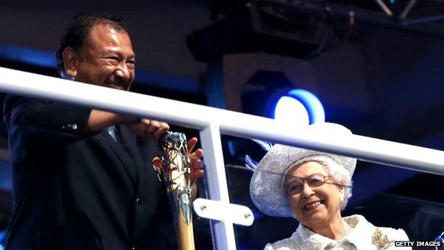Prince Imran the CGF President attempts to retrieve the message from the baton as he presents it to Queen Elizabeth II