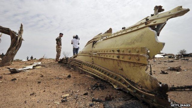 A French soldier and a journalist look at debris of the Air Algerie Flight AH 5017 scattered at the crash site