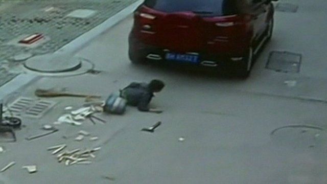 A car drives off after running over a boy in China
