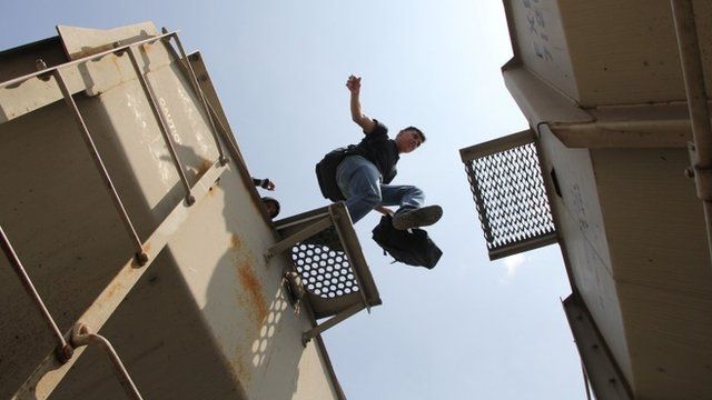 A Central American immigrant jumps between wagons of the so-called La Bestia (The Beast) cargo train, in an attempt to reach the Mexico-US border, in Arriaga, Chiapas state, Mexico on July 16, 2014