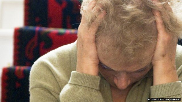 Elderly woman with head in hands